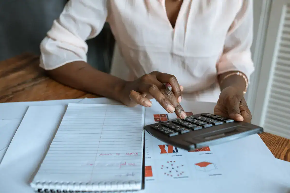 Person calculating expenses for IVF with calculator and documents.